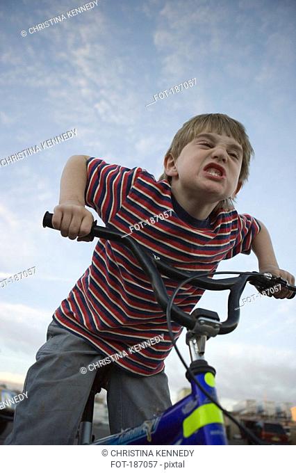 Young boy making face on bicycle