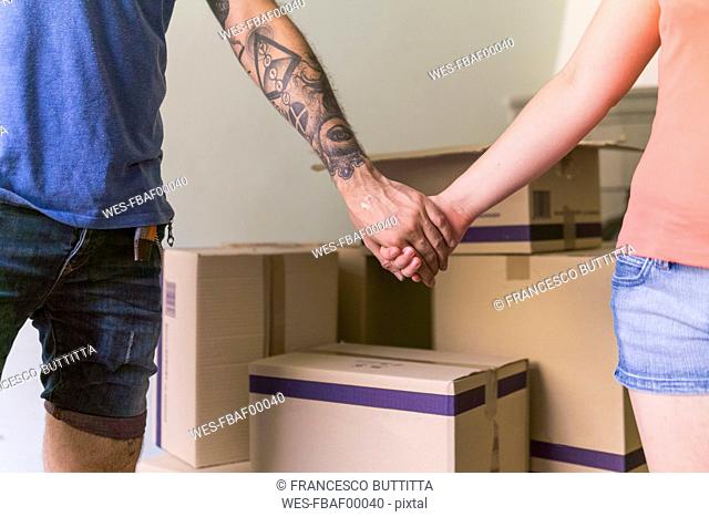 Couple holding hands at new home, partial view