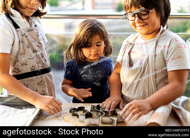 Three children cutting out cookies