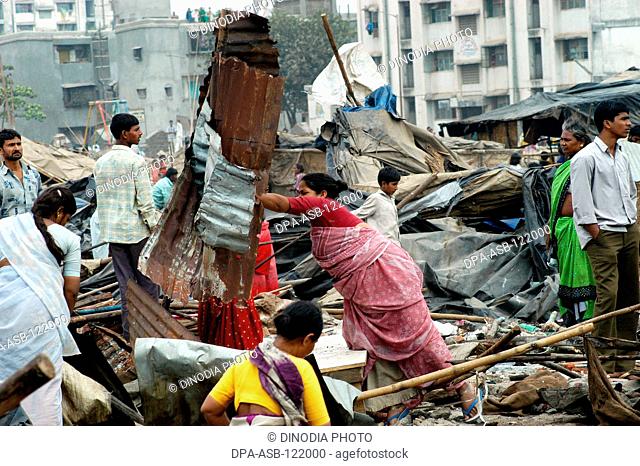 Slum dwellers remove their belongings after the demolition of illegal slums on the Mankhurd Link Road in Bombay now Mumbai ; Maharashtra ; India