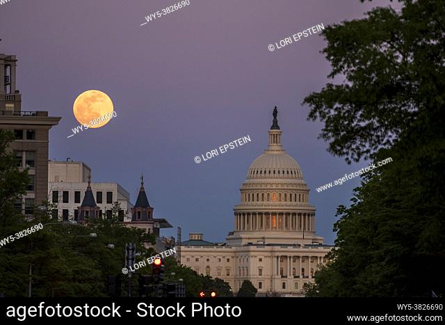 The last rays of the sun set on the United States Capitol Building as the moon rises over Washington, D. C