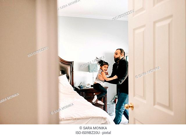 Girl jumping from bed into father's arms