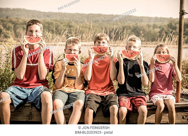 Caucasian children eating watermelon outdoors