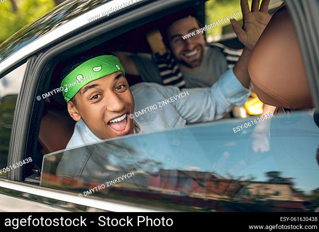 Weekend drive. Group of friends driving in a car and looking excited