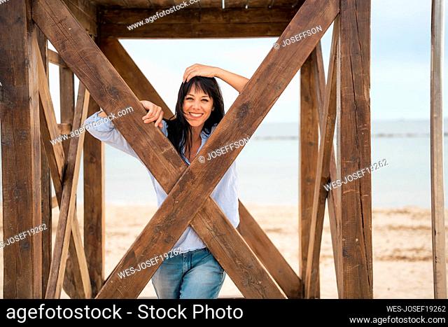 Happy woman standing inside lifeguard hut at beach