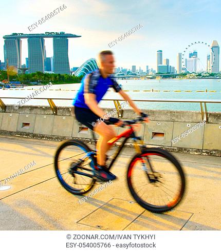 Man riding a bicycle in Singapore bay at sunset