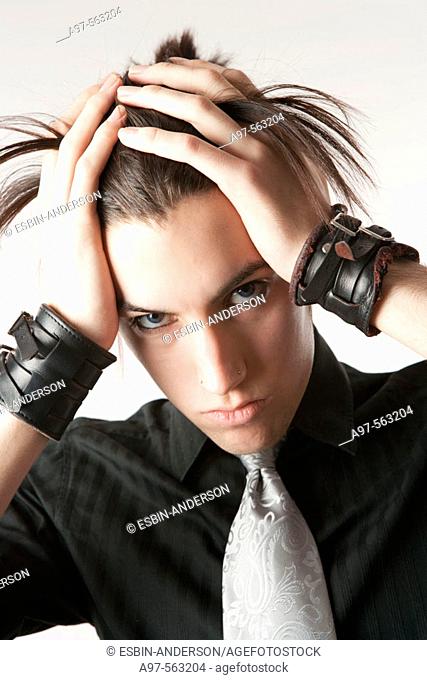 Portrait of teen boy wearing wristbands and a silver tie, pulling his back