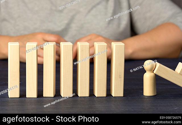 wooden blocks and a figurine of a man stops the fall. The concept of insurance, a strong leader that prevents the company from going bankrupt