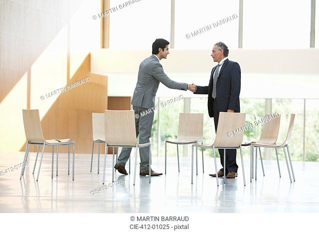 Chairs surrounding businessmen shaking hands