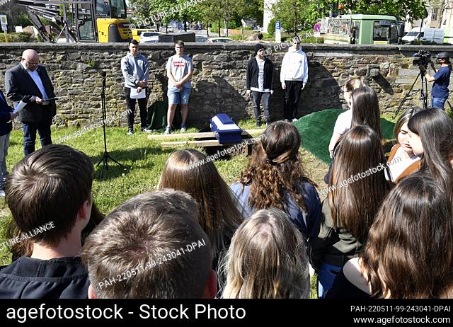 11 May 2022, North Rhine-Westphalia, Schleiden: Pupils of the Johannes-Sturmius-Gymnasium bury the coffin with the bones of a school skeleton in the cemetery