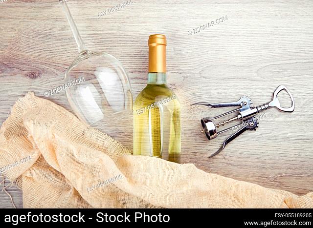 Wine bottle with corkscrew on wooden background