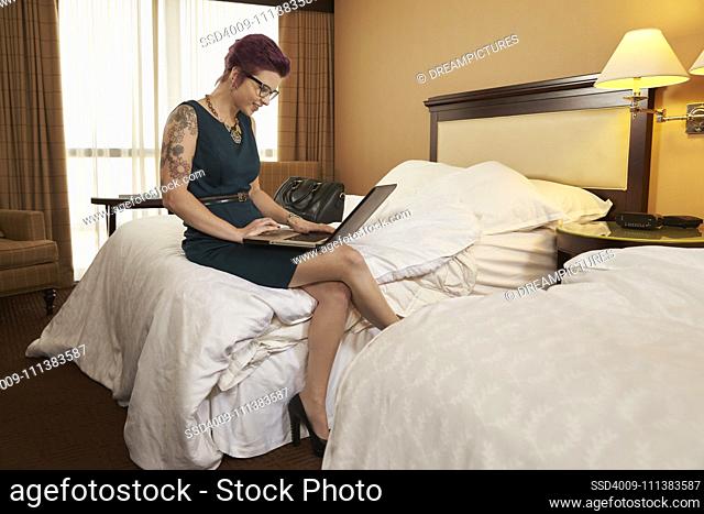 Caucasian woman using laptop on hotel bed