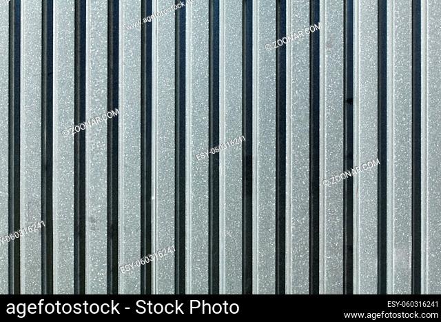 Metal plate fence, sun shining from side. Abstract construction background