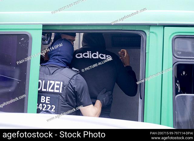 15 July 2020, Berlin: During a police operation in Berlin-Gesundbrunnen, a man is searched by police in a police vehicle as part of a large-scale raid against...