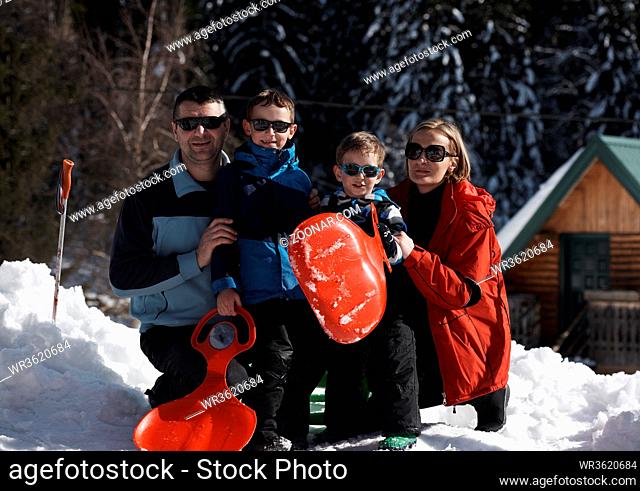 portrait of happy young family sitting on slides at beautiful winter day