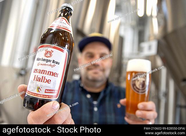 19 May 2021, Bavaria, Nuremberg: Stefan Stretz, Managing Director of the Nuremberg brewery Schanzenbräu, holds a bottle of ""Zusammen Halbe"" beer
