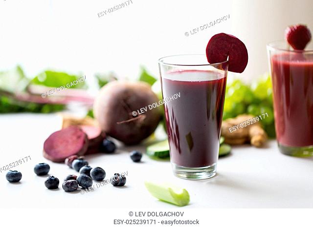 healthy eating, drinks, diet and detox concept - glass of beetroot juice with different fruits and vegetables on table