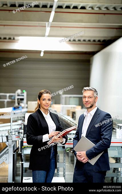 Confident businesswoman with mature businessman at warehouse