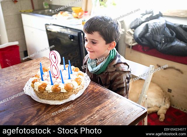 child turns eight years and blows out the candles of the cake