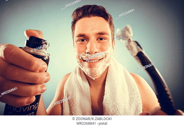 Handsome man with shaving cream foam can and razor