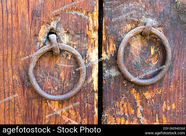 Two rusty iron ring door knobs over an old wooden weathered door