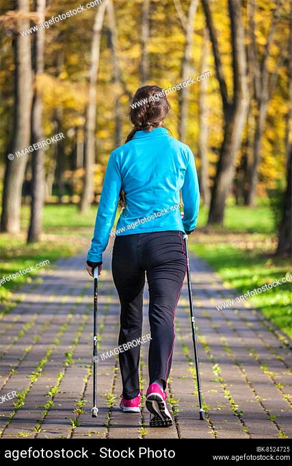 Nordic walking adventure and exercising concept, woman hiking withnordic walking poles in park
