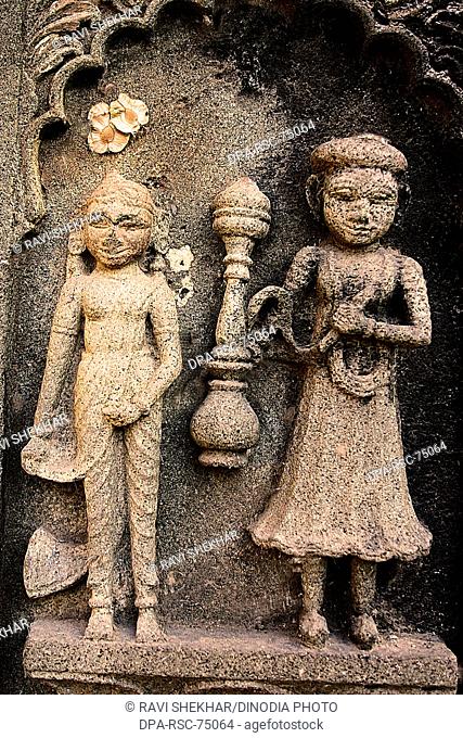 Indian couple , man with Hukka - India’s traditional tobacco pipe in hand , carved on the wall of Ahilayabai temple , ornamental carving on stone