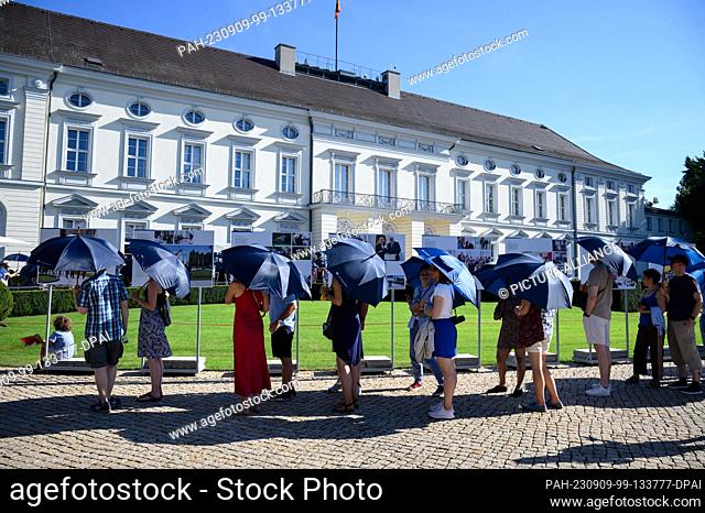 09 September 2023, Berlin: Visitors line up with umbrellas as sun protection at President Steinmeier's Open Palace Day in the park of Bellevue Palace to be...