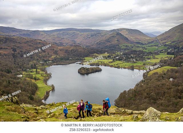 Family of four hiking Loughrigg Fell with Lake Grasmere behind, lake District national park, Cumbria, England