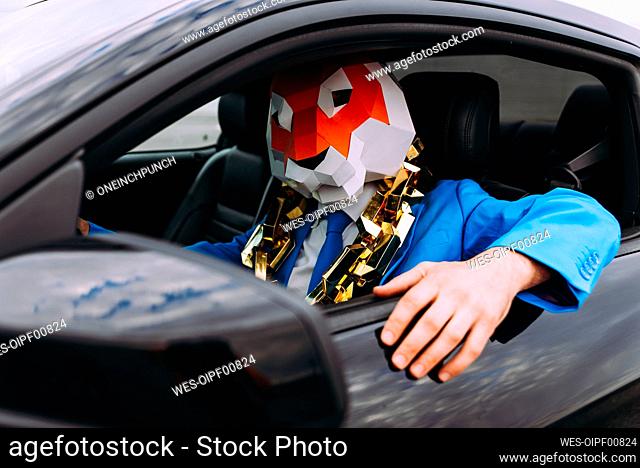 Funny character wearing animal mask and blue business suit in car