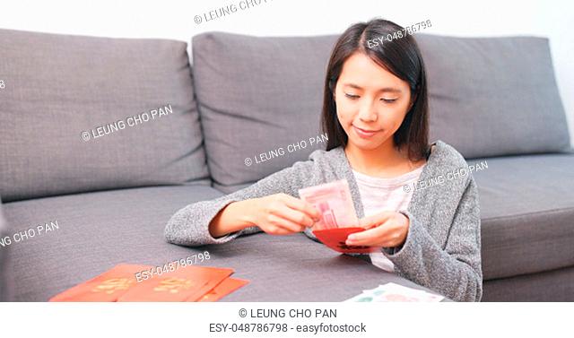 Woman putting banknote into lunar new year red packet