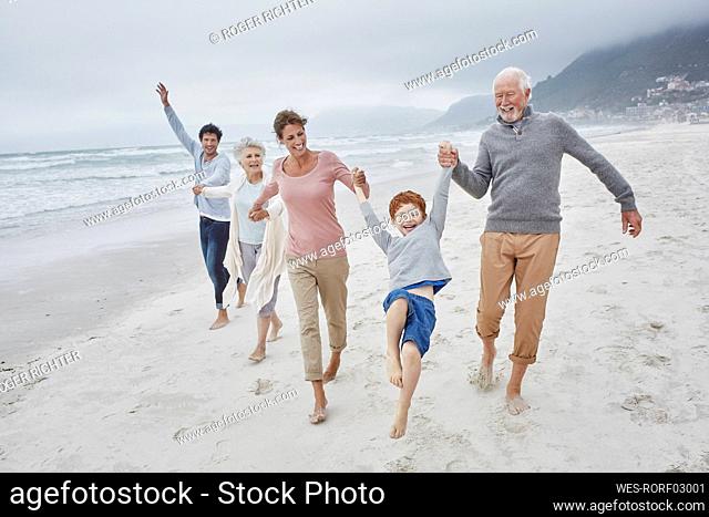 Happy couple spending quality time at the beach with son and grandparents