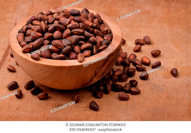 Bowl of cedar nuts on wooden background