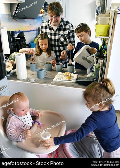 14 May 2021, Saxony, Leipzig: Ronny Steglich prepares tea with the children Timon (r, 11) and Kiana (l, 7) in the eat-in kitchen of their new 5-room apartment