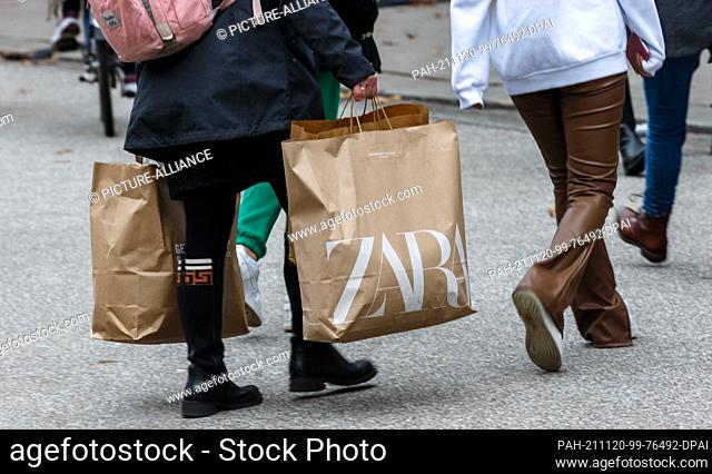 20 November 2021, Hamburg: People walk through the city centre with shopping bags. According to a survey, half of the consumers in Germany want to go bargain...