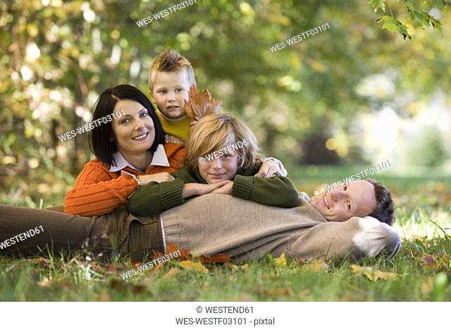 Parents with two children 6-11 lying in meadow, smiling