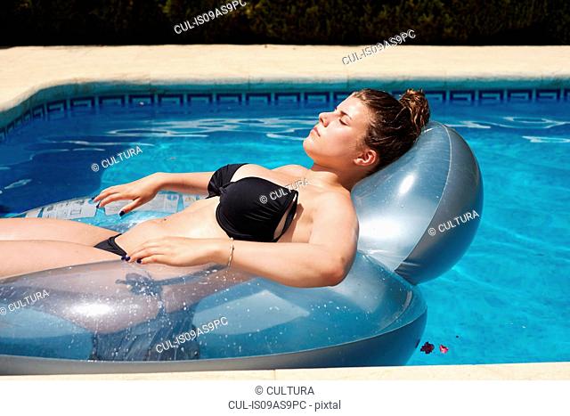 Teenage girl lying on inflatable in swimming pool
