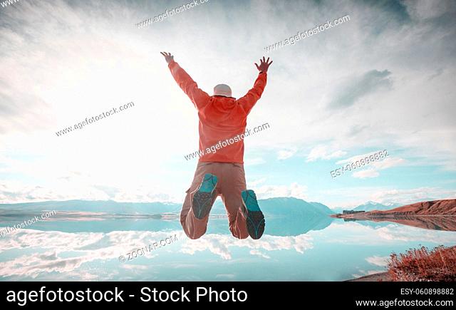 Jumping man above mountains lake