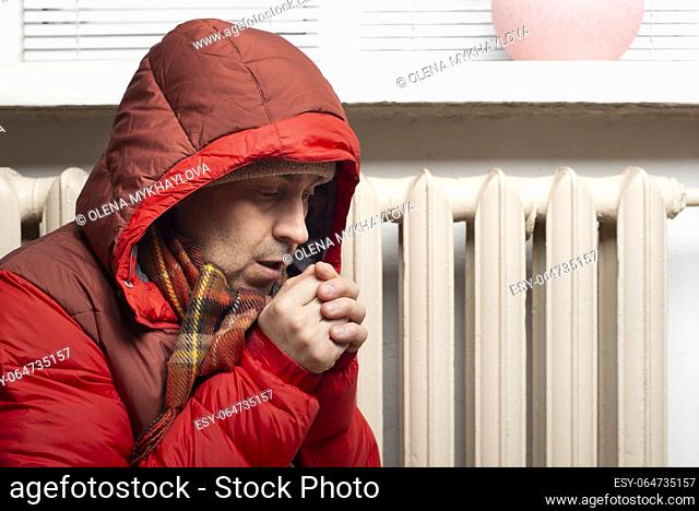 Middle age male model in parka and scarf breathing on his hands