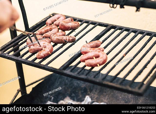Hand cooking sausage meat on metal barbecue grill. Cooking fresh meat on bbq grill outdoor home or restaurant cooking
