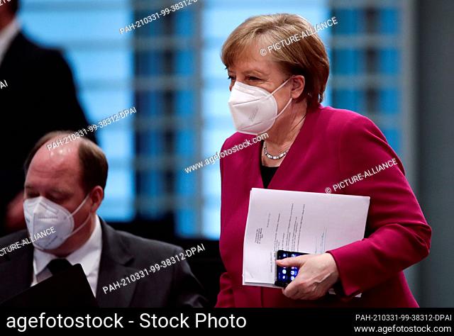 31 March 2021, Berlin: Chancellor Angela Merkel (CDU) arrives at the weekly cabinet meeting at the Chancellor's Office with her documents in hand and passes...
