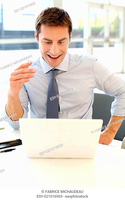 Businessman in front of laptop reading good news