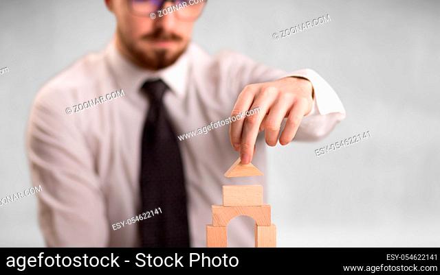 Young handsome businessman using wooden building blocks