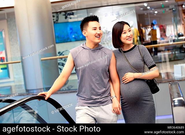 Her husband with his pregnant wife shopping at the mall