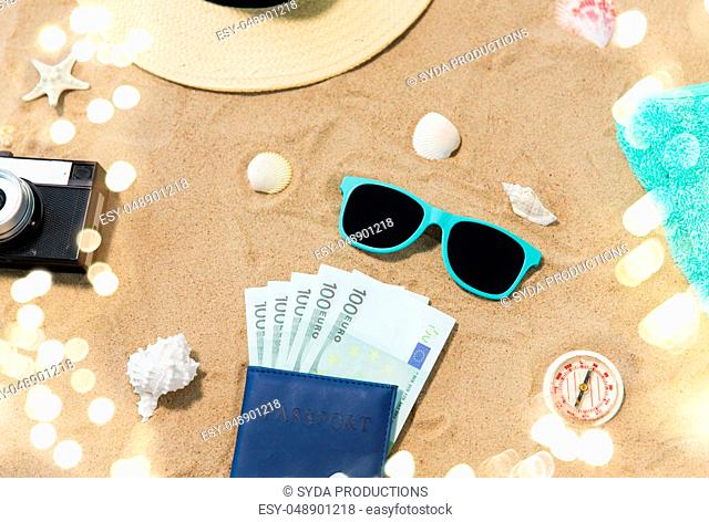 money in passport, shades and hat on beach sand