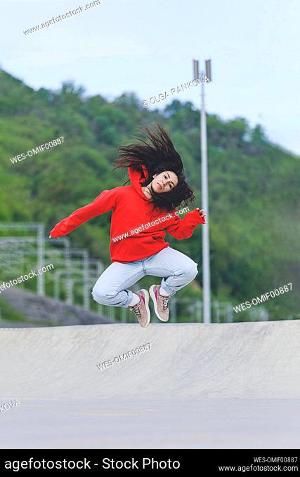 Woman with tousled hair jumping at skateboard park