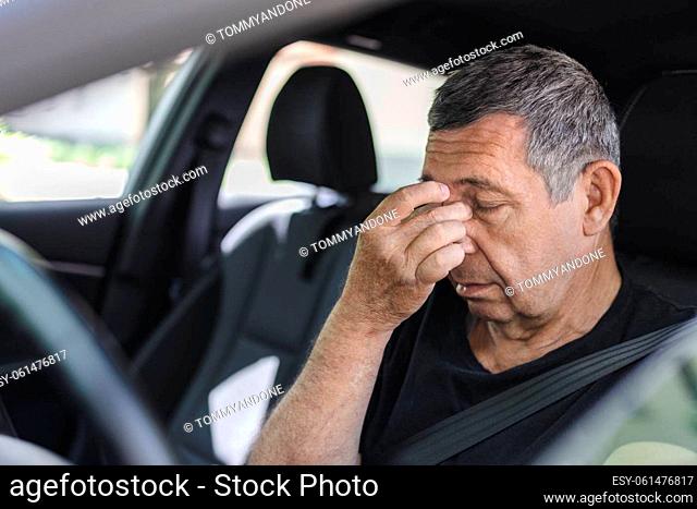 Tired pensioner in his 70s, dring in a car