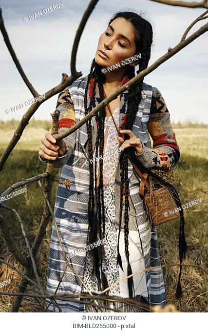 Caucasian woman wearing traditional clothing holding branch