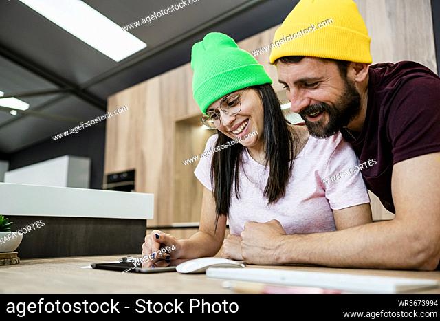 Happy modern business couple using digital tablet at desk in office