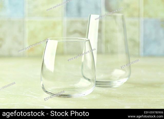 Two empty glasses for water or cocktails on light table. Glasses cup for drinks. Beverage concept